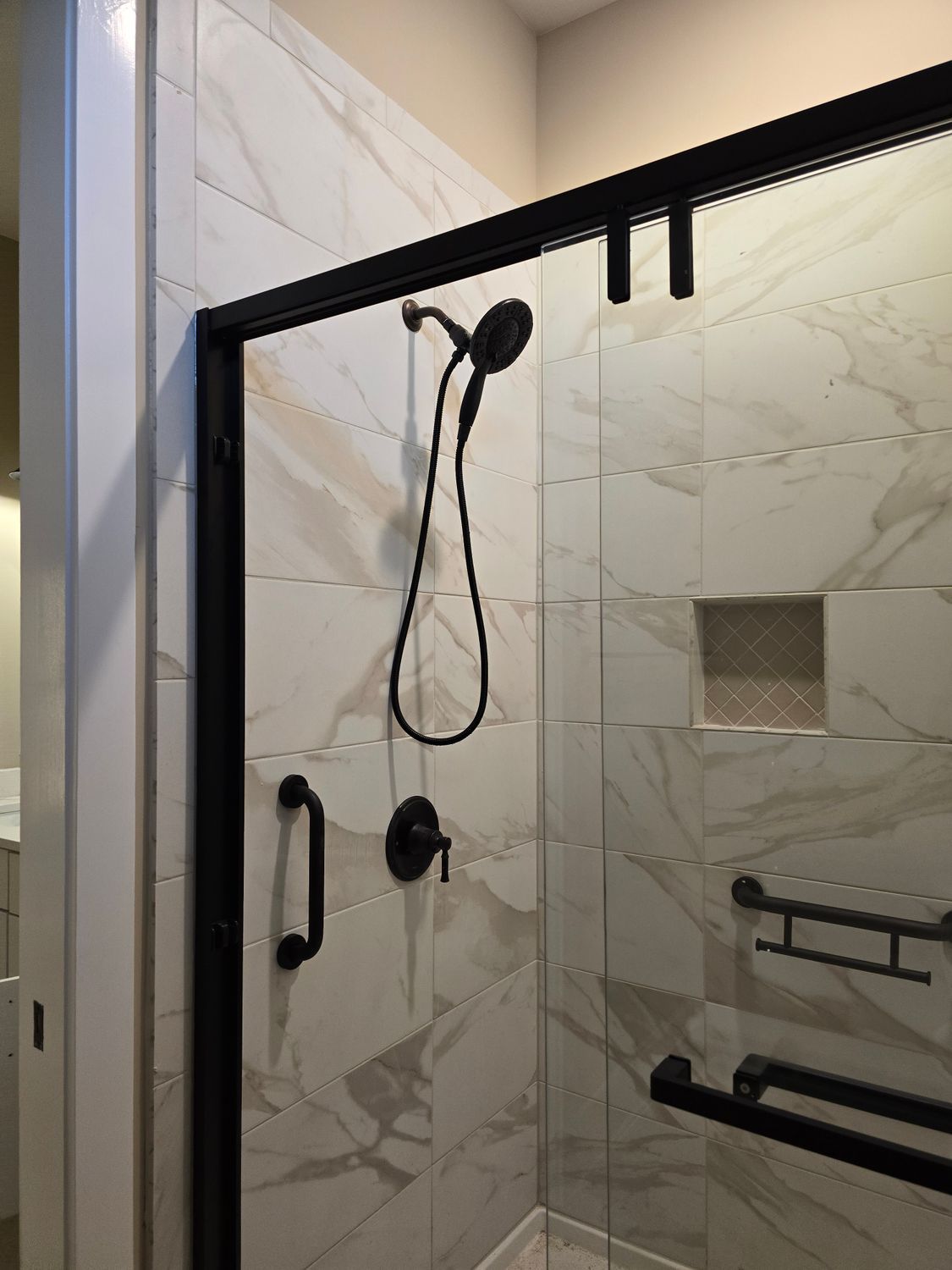 There is a shower with a black frame and a shower head.
