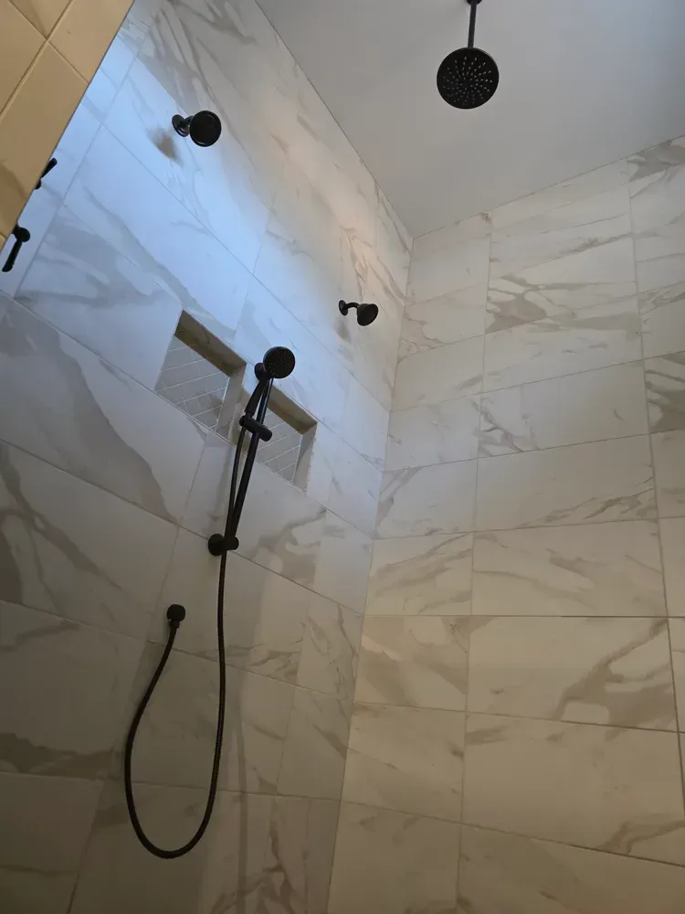 A shower with marble tiles and a black shower head