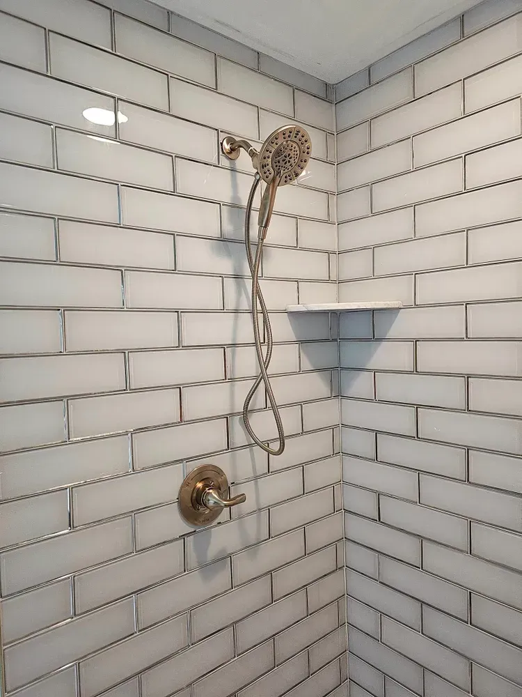 A shower with white brick walls and a shower head