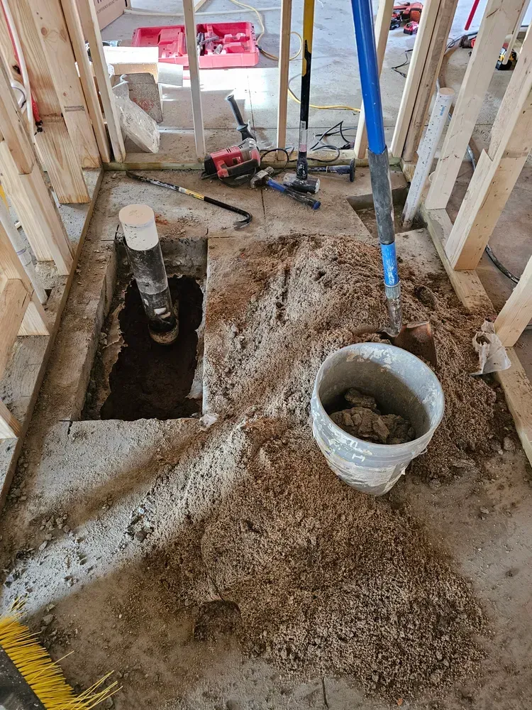 A bucket of dirt is sitting on the floor next to a hole in the floor.