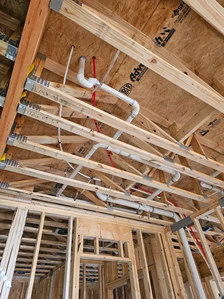 A house is being built with a lot of pipes coming out of the ceiling.