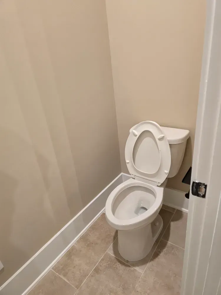 A toilet is sitting in a small bathroom next to a door.
