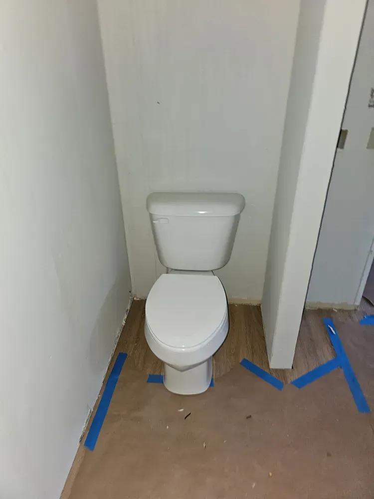 A white toilet is sitting in a small bathroom next to a door.