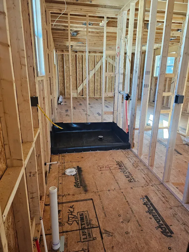A bathroom under construction in a house with a shower tray on the floor.