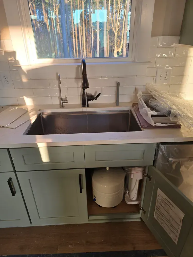 A kitchen sink with a water filter underneath it.