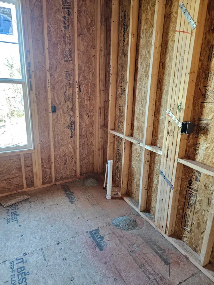 A room with wooden walls and a window in a house under construction.