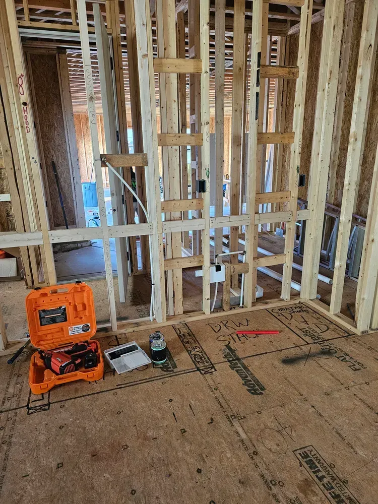 A box of tools is sitting on the floor in a room under construction.