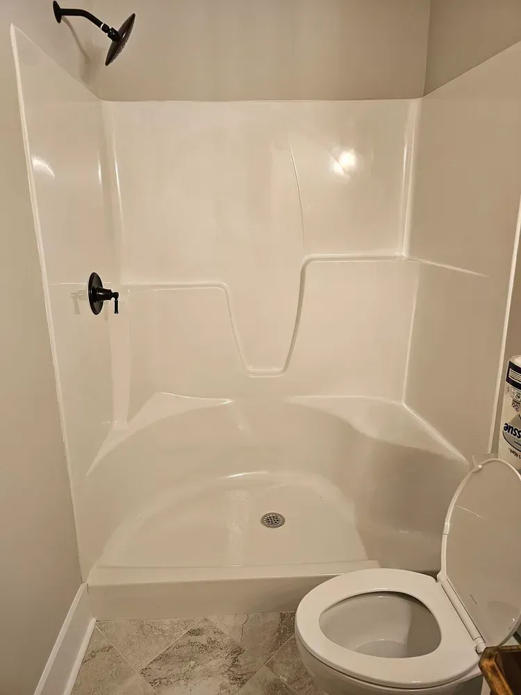 A bathroom with a toilet , shower , and shower head.