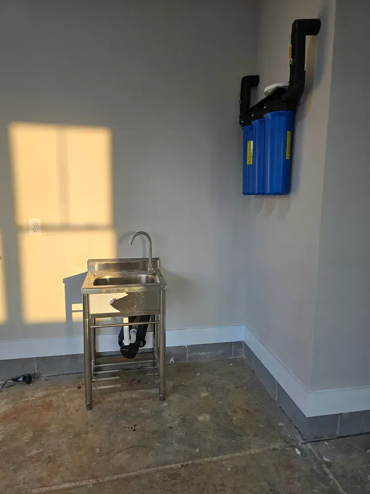 A stainless steel sink is in a room next to a window.