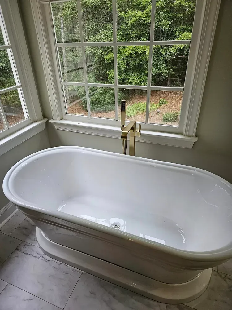 A white bathtub is sitting in a bathroom next to a window.