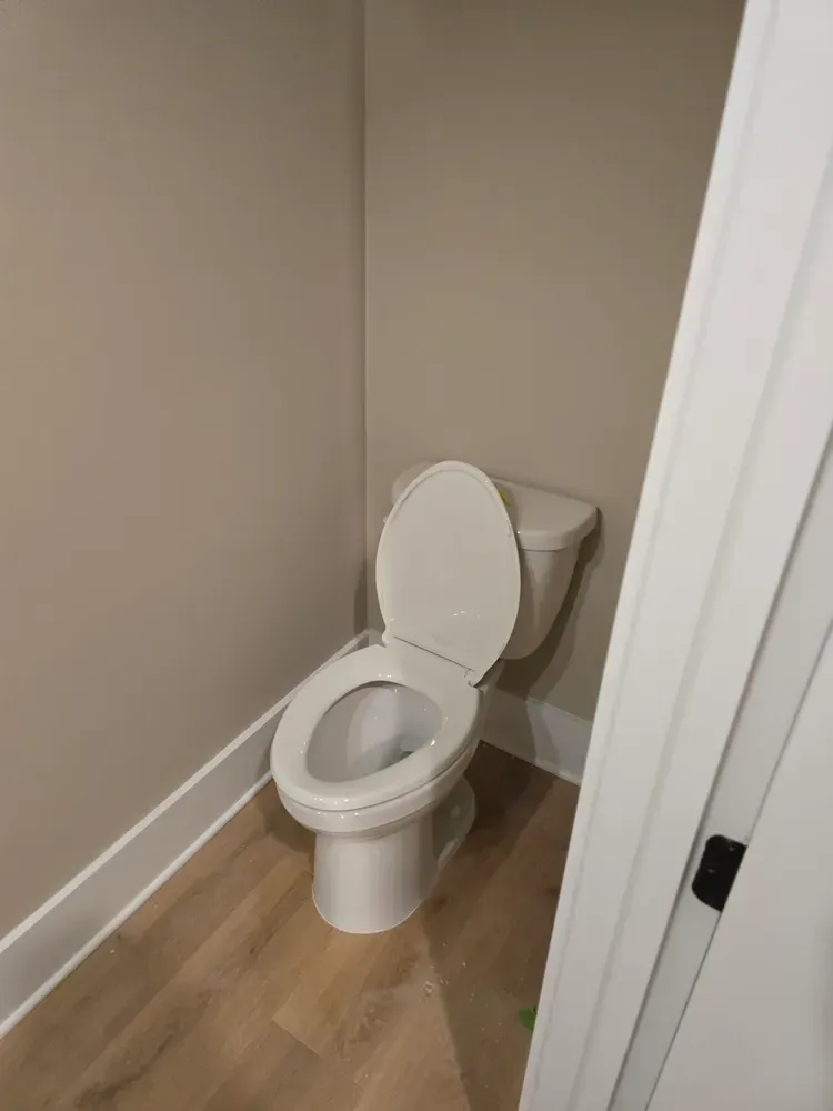 A toilet is sitting in a corner of a bathroom next to a door.