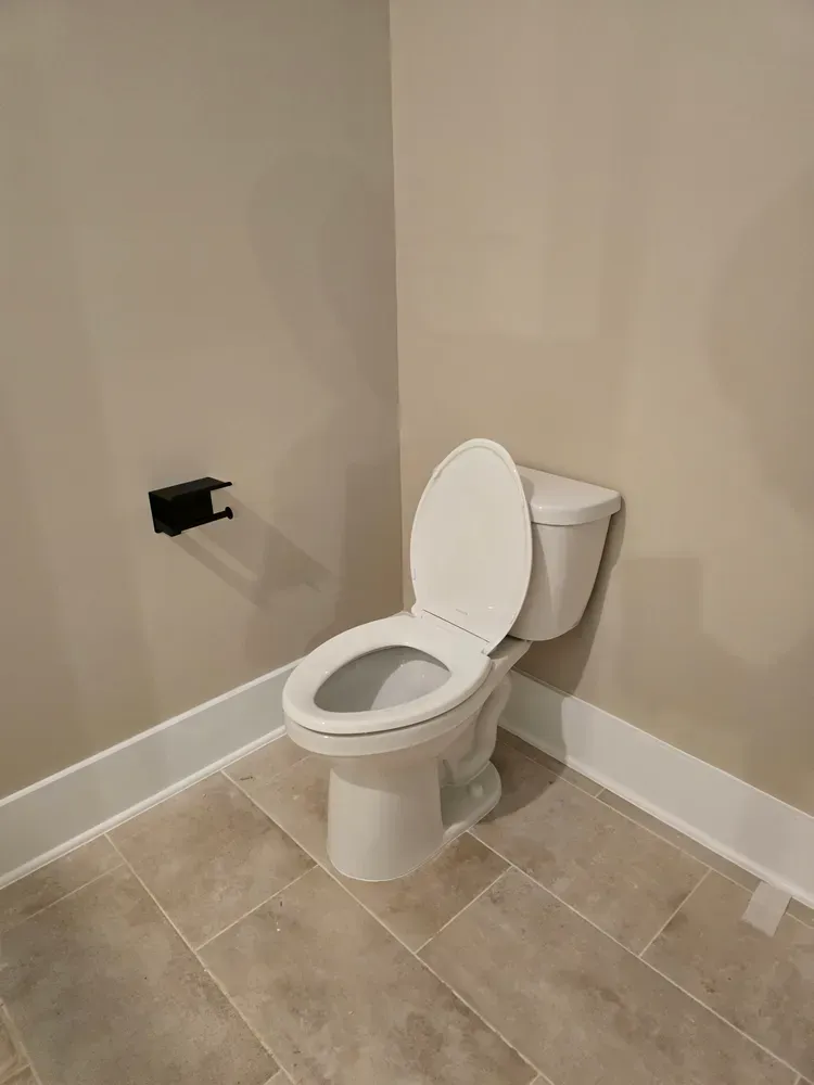A white toilet is sitting in a bathroom next to a wall.