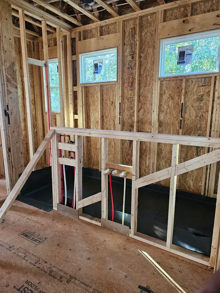A room in a house under construction with wooden walls and windows.