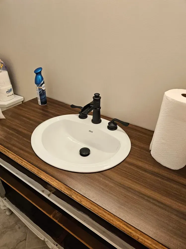 A bathroom sink is sitting on top of a wooden counter.