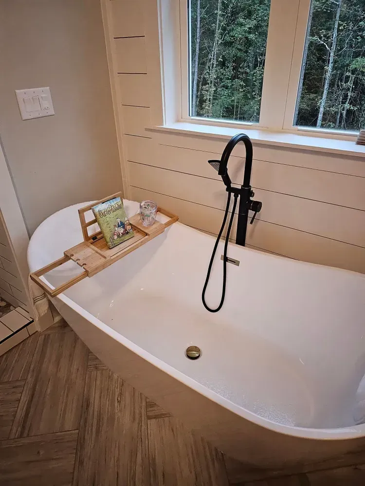 A bathtub in a bathroom next to a window.