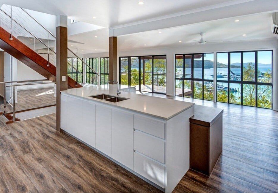 Modern Open-Plan Kitchen with Water Views and Wooden Flooring — Coral Coast Building & Management in Cannon Valley, QLD