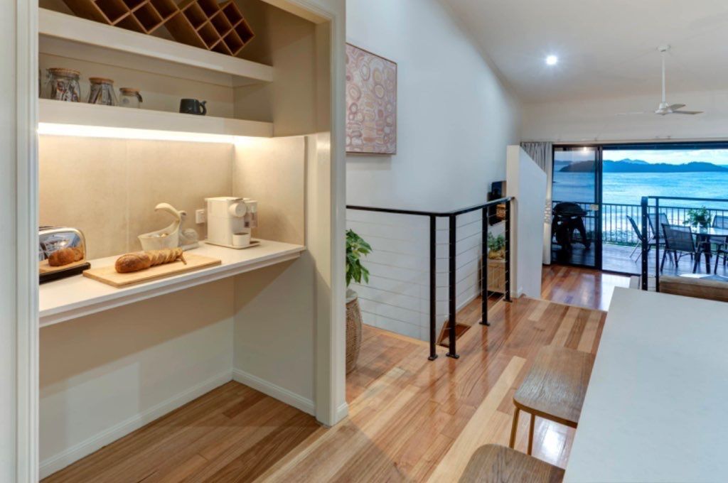 A Kitchen With Hardwood Floors and a Sliding Glass Door Leading to a Balcony — Coral Coast Building & Management in Cannon Valley, QLD