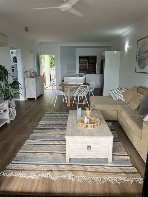 A Living Room With a Couch , Table , Chairs and a Rug — Coral Coast Building & Management in Cannon Valley, QLD