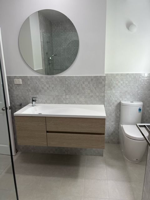 A Bathroom With a Sink , Toilet , and Mirror — Coral Coast Building & Management in Cannon Valley, QLD