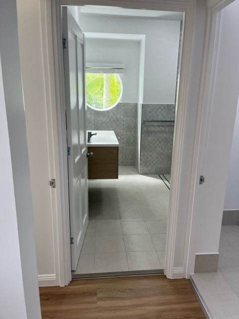 A Hallway Leading to a Bathroom With a Sink and a Window — Coral Coast Building & Management in Cannon Valley, QLD