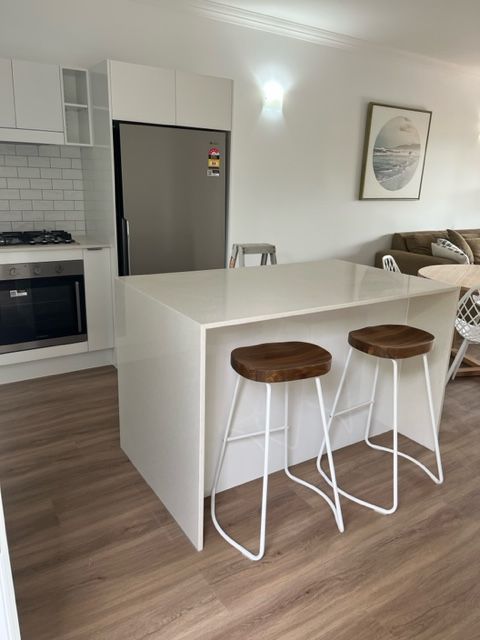 A Kitchen With Two Stools and a Refrigerator — Coral Coast Building & Management in Cannon Valley, QLD
