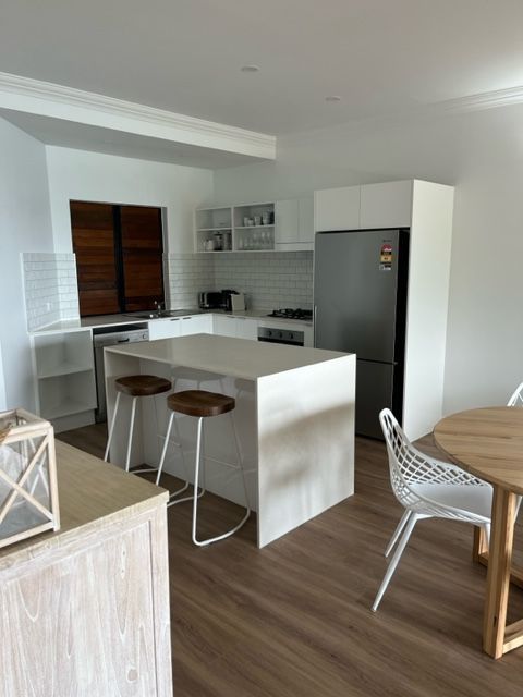 A Kitchen With a Table and Chairs and a Refrigerator — Coral Coast Building & Management in Cannon Valley, QLD