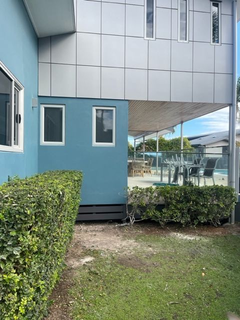 A Blue Building With a Balcony and a Hedge in Front of It — Coral Coast Building & Management in Cannon Valley, QLD