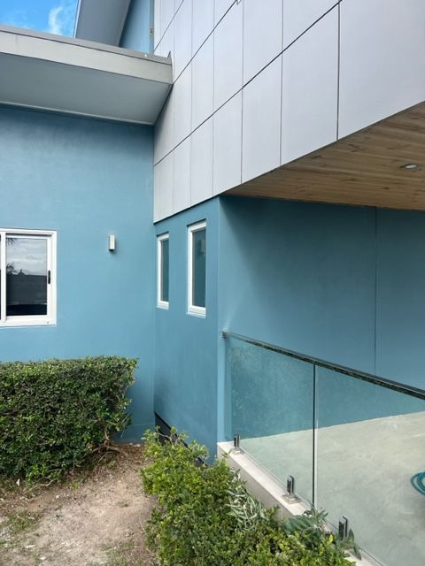 A Blue Building With White Windows and a Glass Railing — Coral Coast Building & Management in Cannon Valley, QLD