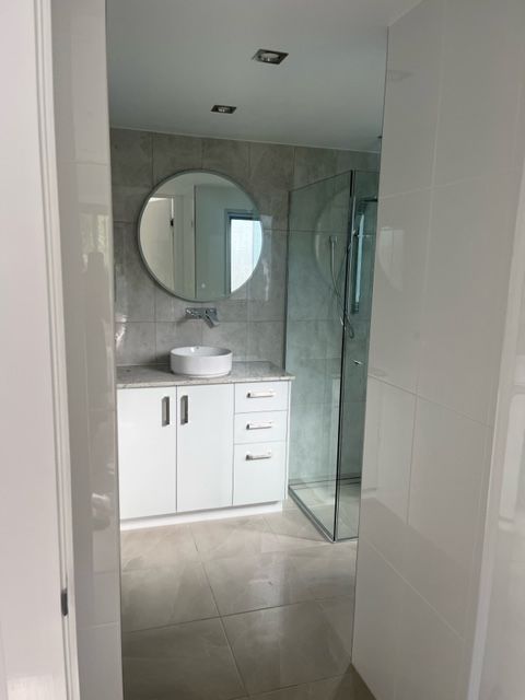 A Bathroom With a Sink , Mirror and Walk in Shower — Coral Coast Building & Management in Cannon Valley, QLD