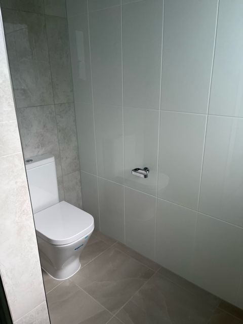 There is a Toilet in the Bathroom With White Tiles — Coral Coast Building & Management in Cannon Valley, QLD