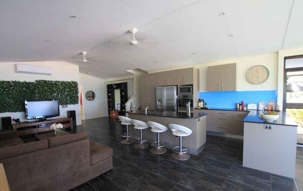 A Living Room With a Couch , Television , and Kitchen — Coral Coast Building & Management in Cannon Valley, QLD