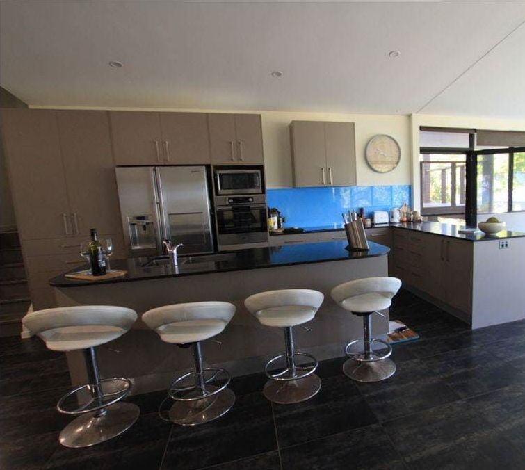 A Kitchen With Stools and a Refrigerator in It — Coral Coast Building & Management in Cannon Valley, QLD