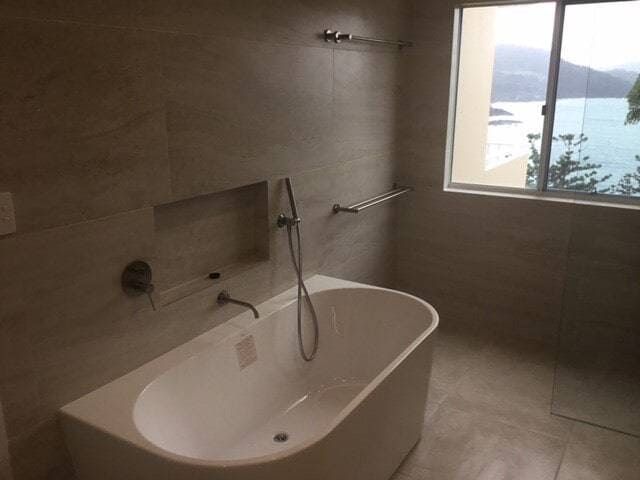 A Bathtub in a Bathroom With a View of the Ocean — Coral Coast Building & Management in Cannon Valley, QLD