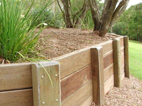A Wooden Retaining Wall With Plants Growing Out of It — Coral Coast Building & Management in Cannon Valley, QLD