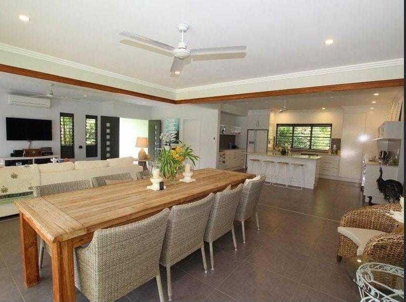 A Dining Room With a Long Table and Chairs and a Ceiling Fan — Coral Coast Building & Management in Cannon Valley, QLD