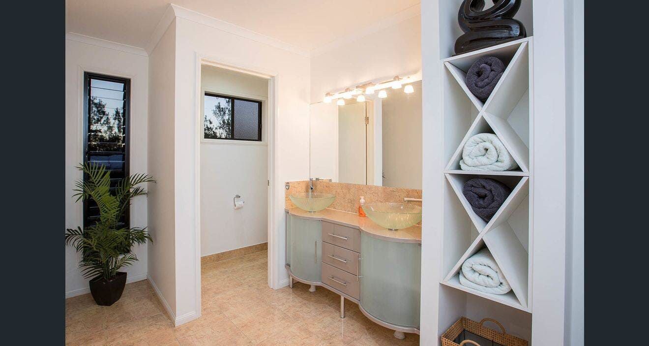 A Bathroom With Two Sinks and a Shelf Filled With Towels — Coral Coast Building & Management in Cannon Valley, QLD