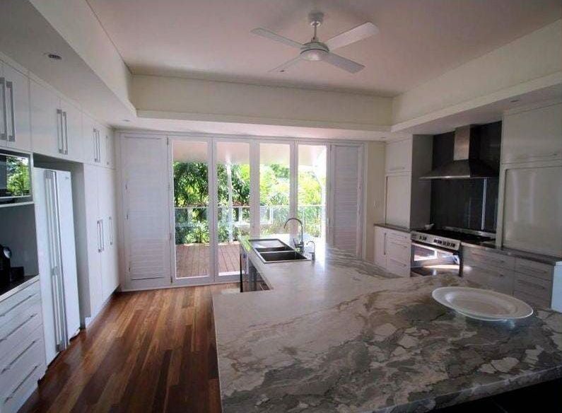 A Kitchen With Granite Counter Tops and a Ceiling Fan — Coral Coast Building & Management in Cannon Valley, QLD