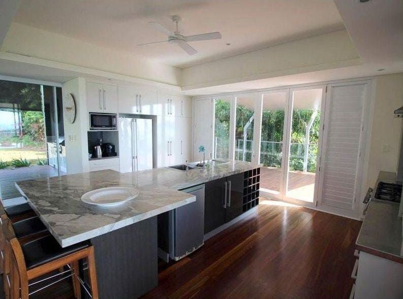 A Kitchen With a Large Island and Sliding Glass Doors — Coral Coast Building & Management in Cannon Valley, QLD