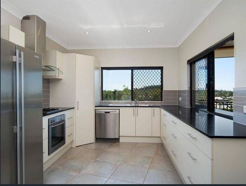 An Empty Kitchen With Stainless Steel Appliances and Black Counter Tops — Coral Coast Building & Management in Cannon Valley, QLD