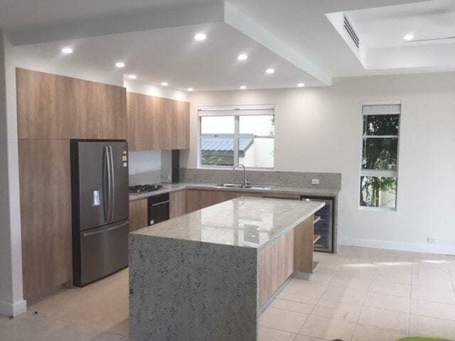 A Kitchen With a Large Island and Stainless Steel Appliances — Coral Coast Building & Management in Cannon Valley, QLD