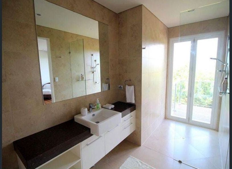 A Bathroom With a Sink , Mirror and Sliding Glass Doors — Coral Coast Building & Management in Cannon Valley, QLD