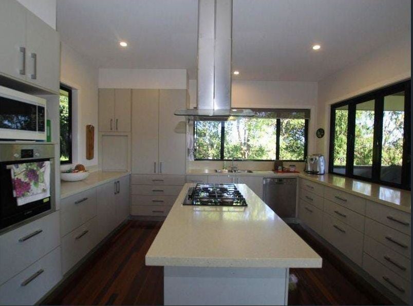 A Kitchen With White Cabinets and a Large Island in the Middle — Coral Coast Building & Management in Cannon Valley, QLD