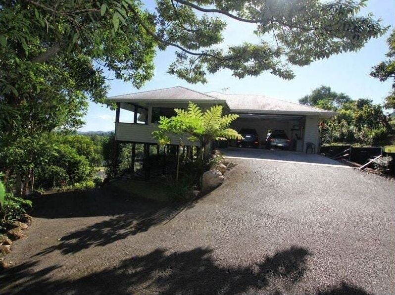 A Large House With a Driveway Leading to It is Surrounded by Trees — Coral Coast Building & Management in Cannon Valley, QLD