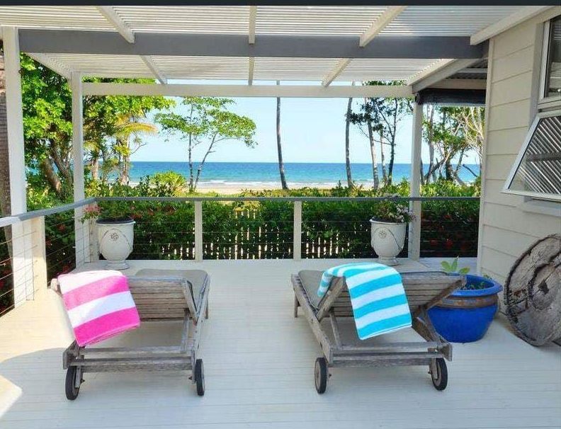 Two Lounge Chairs With Towels on Them Are on a Patio Overlooking the Ocean — Coral Coast Building & Management in Cannon Valley, QLD