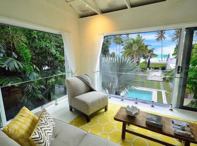 A Living Room With a Couch , Chair , Coffee Table and a View of a Pool — Coral Coast Building & Management in Cannon Valley, QLD