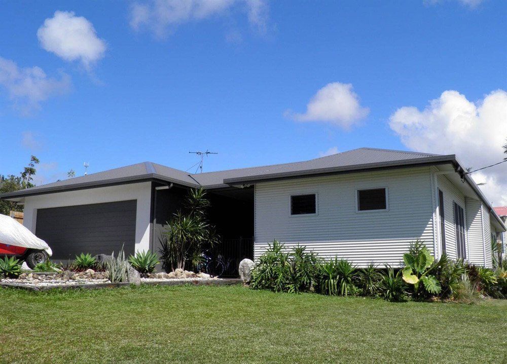 A House With a Boat Parked in Front of It — Coral Coast Building & Management in Cannon Valley, QLD