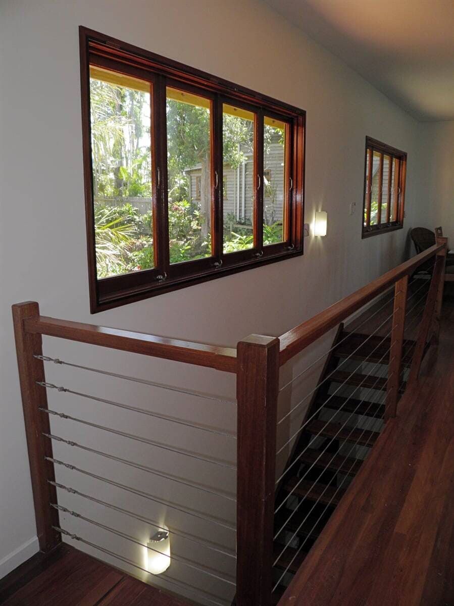A Staircase With a Wooden Railing and Lots of Windows — Coral Coast Building & Management in Cannon Valley, QLD