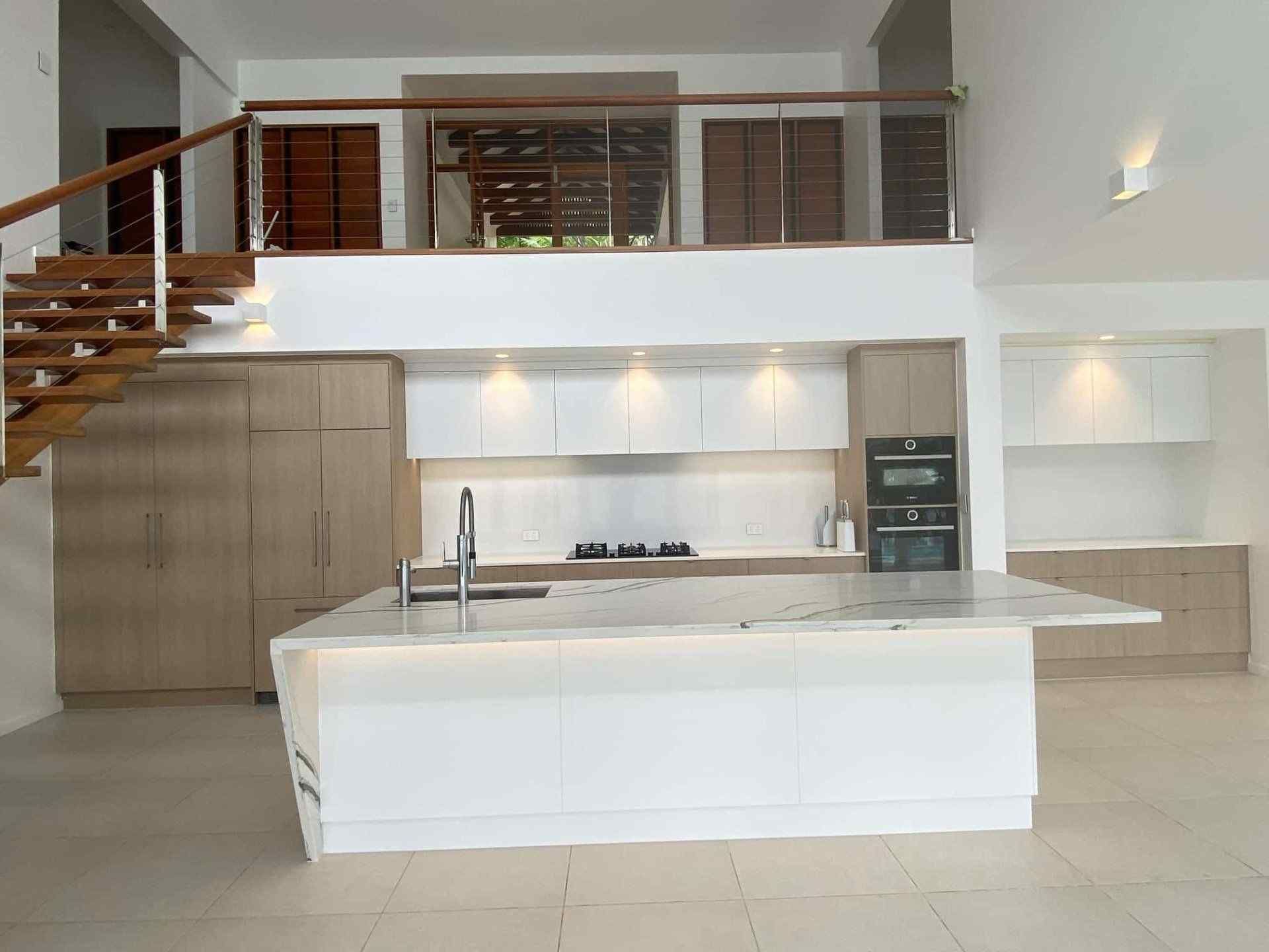 A Kitchen With a Large Island and Stairs Leading to the Second Floor — Coral Coast Building & Management in Cannon Valley, QLD