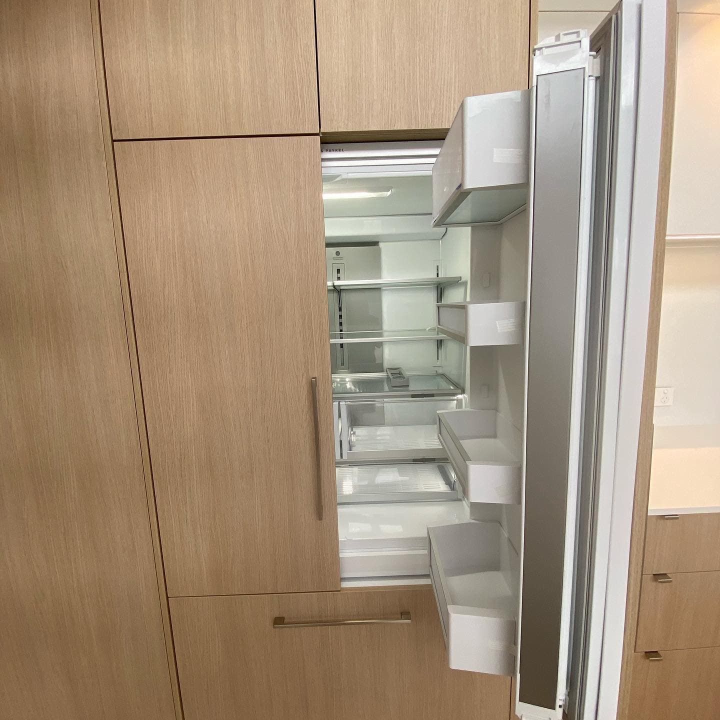 A Refrigerator With the Door Open in a Kitchen With Wooden Cabinets — Coral Coast Building & Management in Cannon Valley, QLD