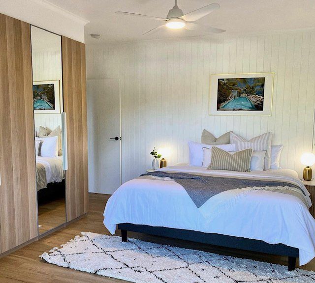 A Bedroom With a Large Bed and a Ceiling Fan — Coral Coast Building & Management in Cannon Valley, QLD